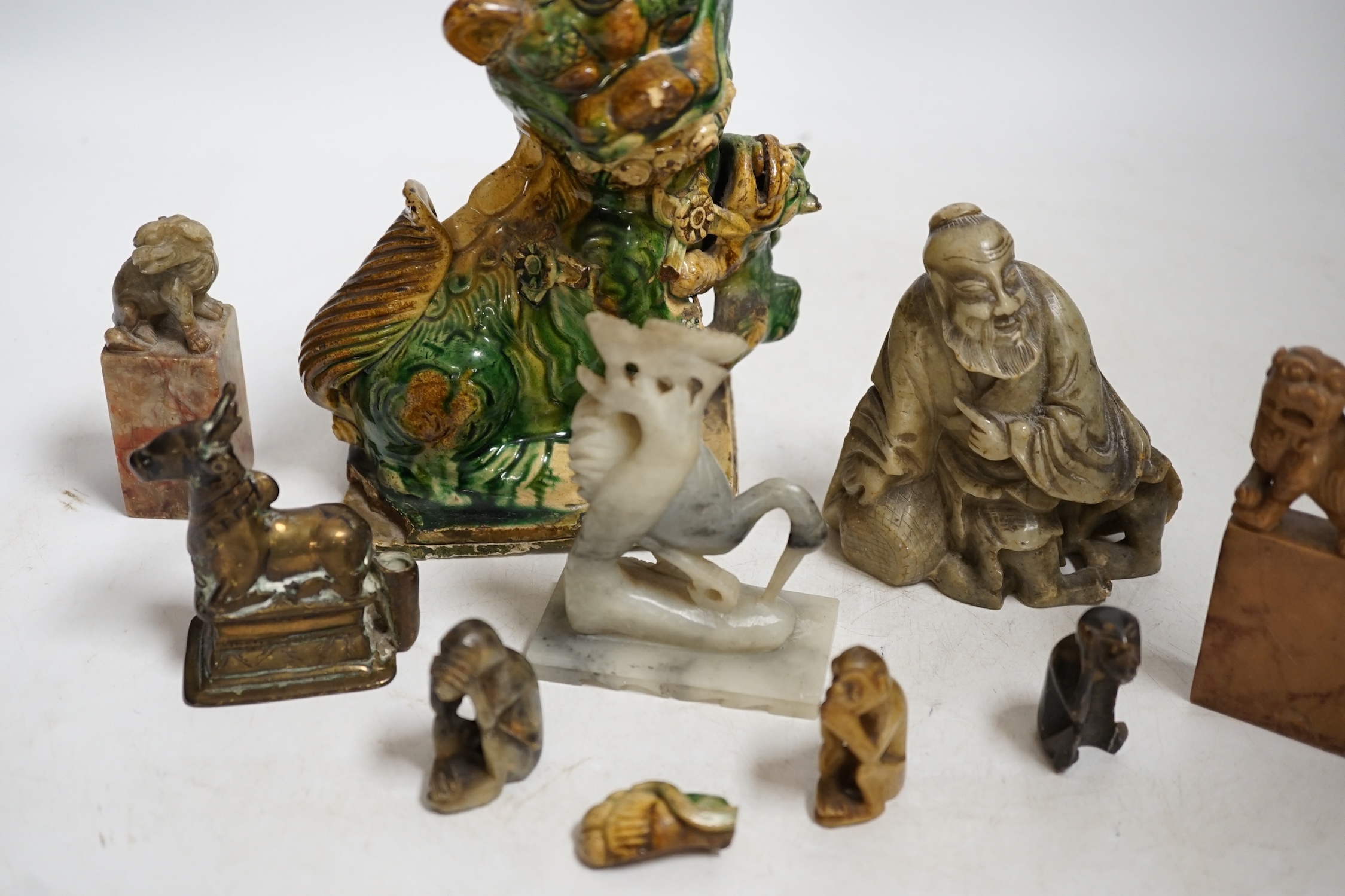 A glazed Chinese lion dog and a collection of soapstone carvings including seals, largest 17cm high. Condition - varies, poor to fair